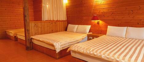 A cabin with two beds, wooden walls, and a small table with a lamp.