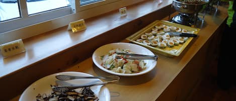 A buffet table with various dishes, including sliced mushrooms, a salad, and boiled eggs.