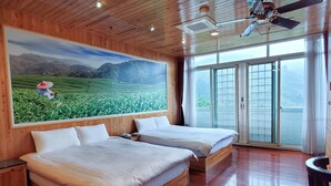 A room with two wooden beds, a ceiling fan, and a large window with a view of a green landscape. - King Taiwan (Lugu)