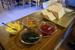 Una mesa de buffet con diversos alimentos, como pan, crema de cacahuete y pastas untables.