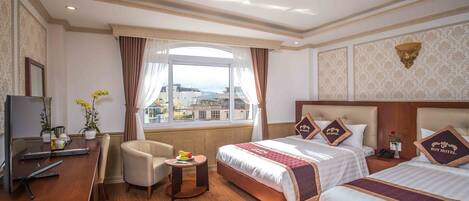 A hotel room with two beds, a desk, a chair, a small table, and a large window with a view.
