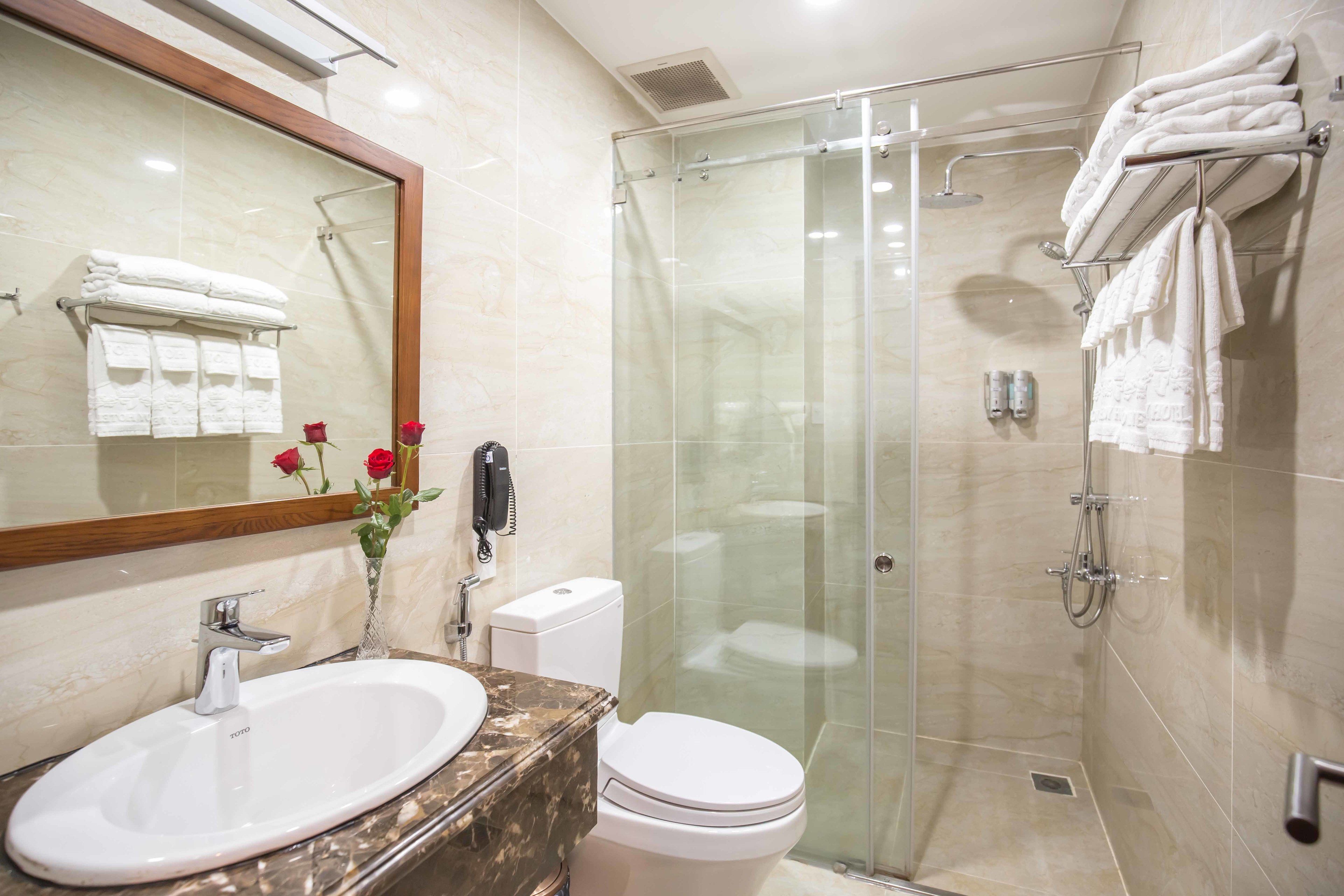Un baño moderno con ducha envuelta en vidrio, lavamanos de mármol y un inodoro.