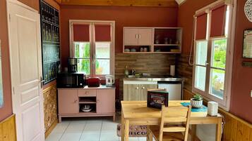 A compact kitchen with a dining area, wooden cabinets, a microwave, a toaster, and a window with a view of greenery.