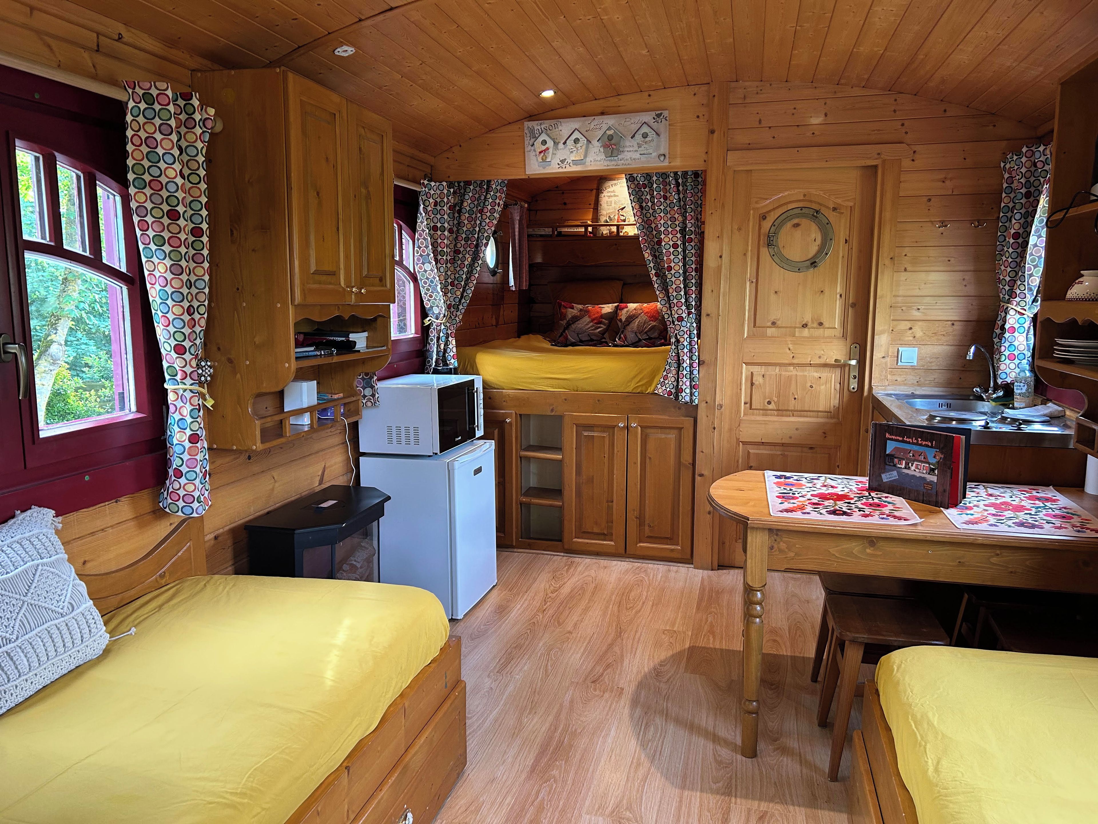 Een gezellig chaletinterieur met een bed, een kleine kitchenette en een eethoek.