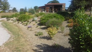 Un bâtiment doté d’un toit rouge, entouré d’un jardin où poussent différentes plantes et fleurs.