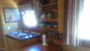 Une cuisine en bois avec un évier, une cuisinière et une fenêtre avec des rideaux.