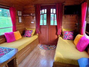 Una cabaña acogedora con dos camas de madera, una mesita y un televisor.