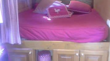 A compact room with a bunk bed, a small wooden desk, and a chair.