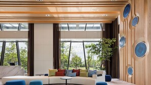 A modern living room with a curved sofa, blue ottomans, and a small table. - Lakeshore Hotel Yilan (Yilan)