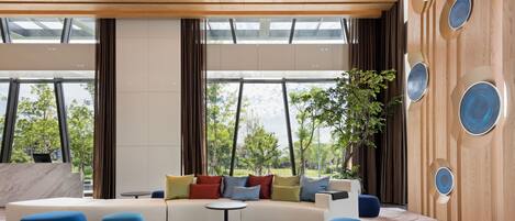 A modern living room with a curved sofa, blue ottomans, and a small table.