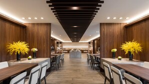 A modern dining area with wooden walls, a central island, and chairs arranged around tables. - Lakeshore Hotel Yilan (Yilan)