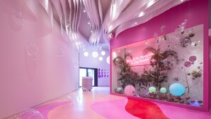 A modern interior with a pink and white color scheme, featuring a unique ceiling design and a decorative glass display with plants and bubbles. - Lakeshore Hotel Yilan (Yilan)