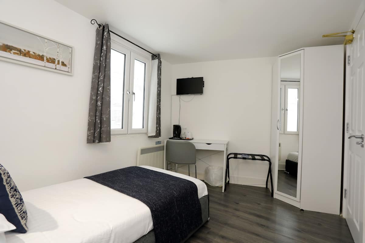 A bedroom with a bed, a desk, a chair, a television, and a wardrobe.