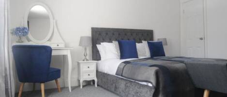 A bedroom with a bed, a dresser, a chair, a mirror, and a nightstand.