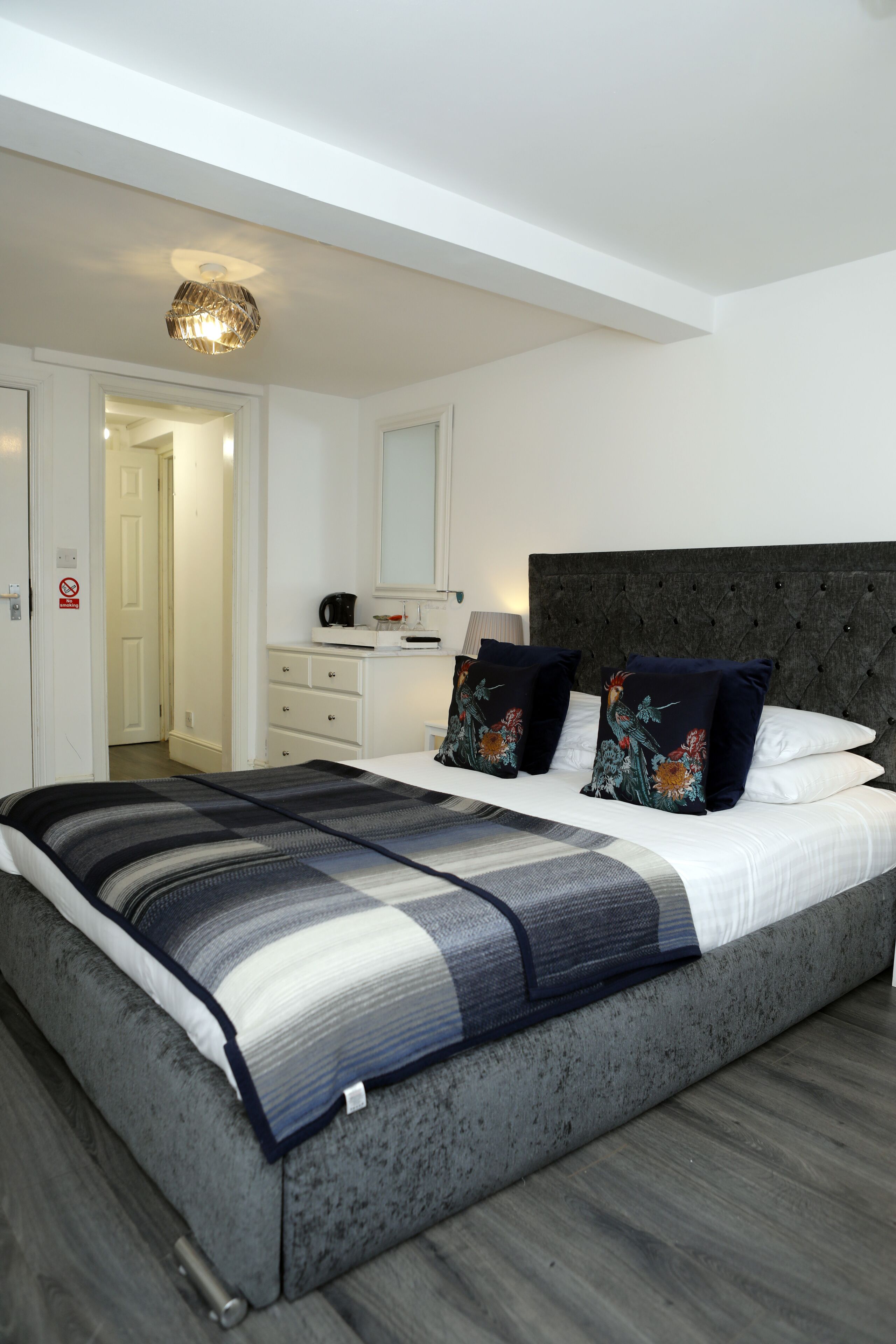 Une chambre à coucher moderne avec un grand lit, une tête de lit sombre et une table de chevet avec une lampe.