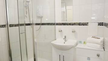 Un baño moderno con ducha de vidrio, lavamanos blanco y retrete.