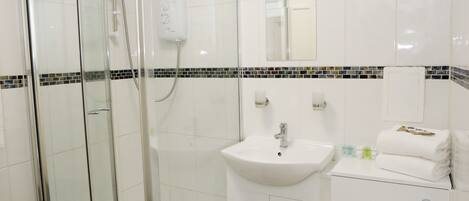 A modern bathroom with a glass-enclosed shower, a white sink, and a toilet.