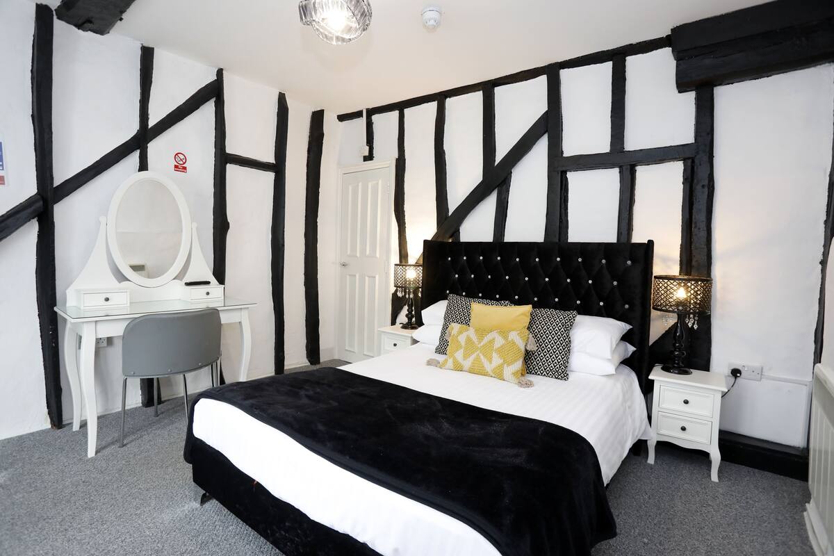 A bedroom with a bed, a dresser, a mirror, and a nightstand.