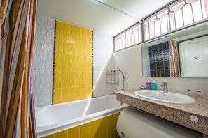Um banheiro com banheira, pia e espelho.