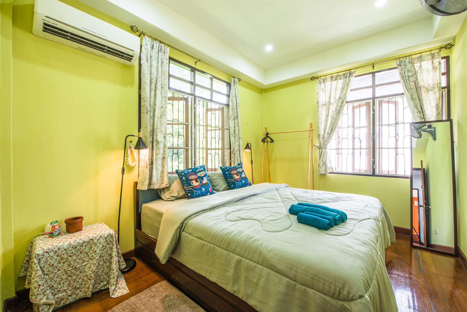A bedroom with a bed, a small table, and a window with curtains.