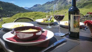 A dining table set with a bottle of wine, glasses, plates of food, and a bowl of soup. - Marmore (Valtournenche)