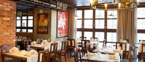 Un restaurant avec des tables et des chaises en bois, un mur en briques et une grande fenêtre.