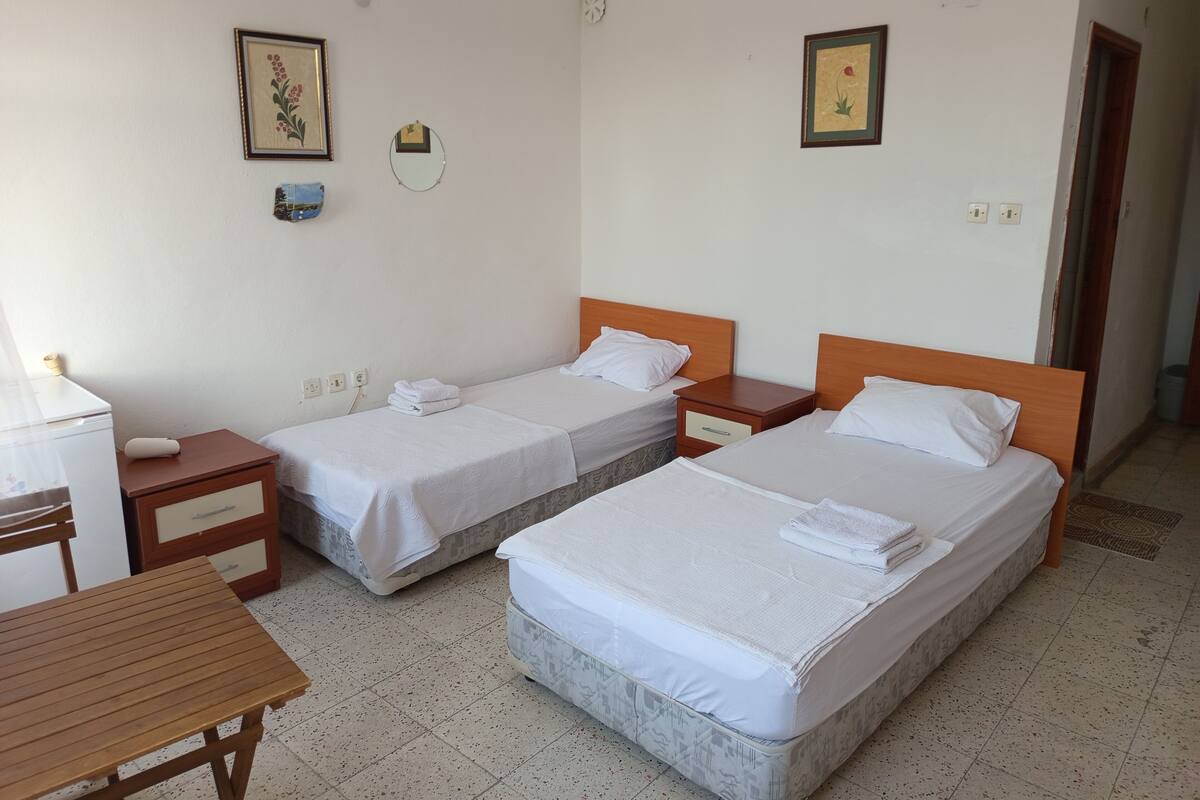 A hotel room with two single beds, a wooden table, and a small desk with a chair.