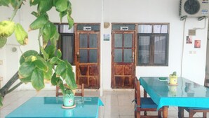 Une pièce dotée de deux portes en bois, portant les numéros 9 et 8, une table recouverte d’une nappe bleue et une plante en pot posée sur la table.