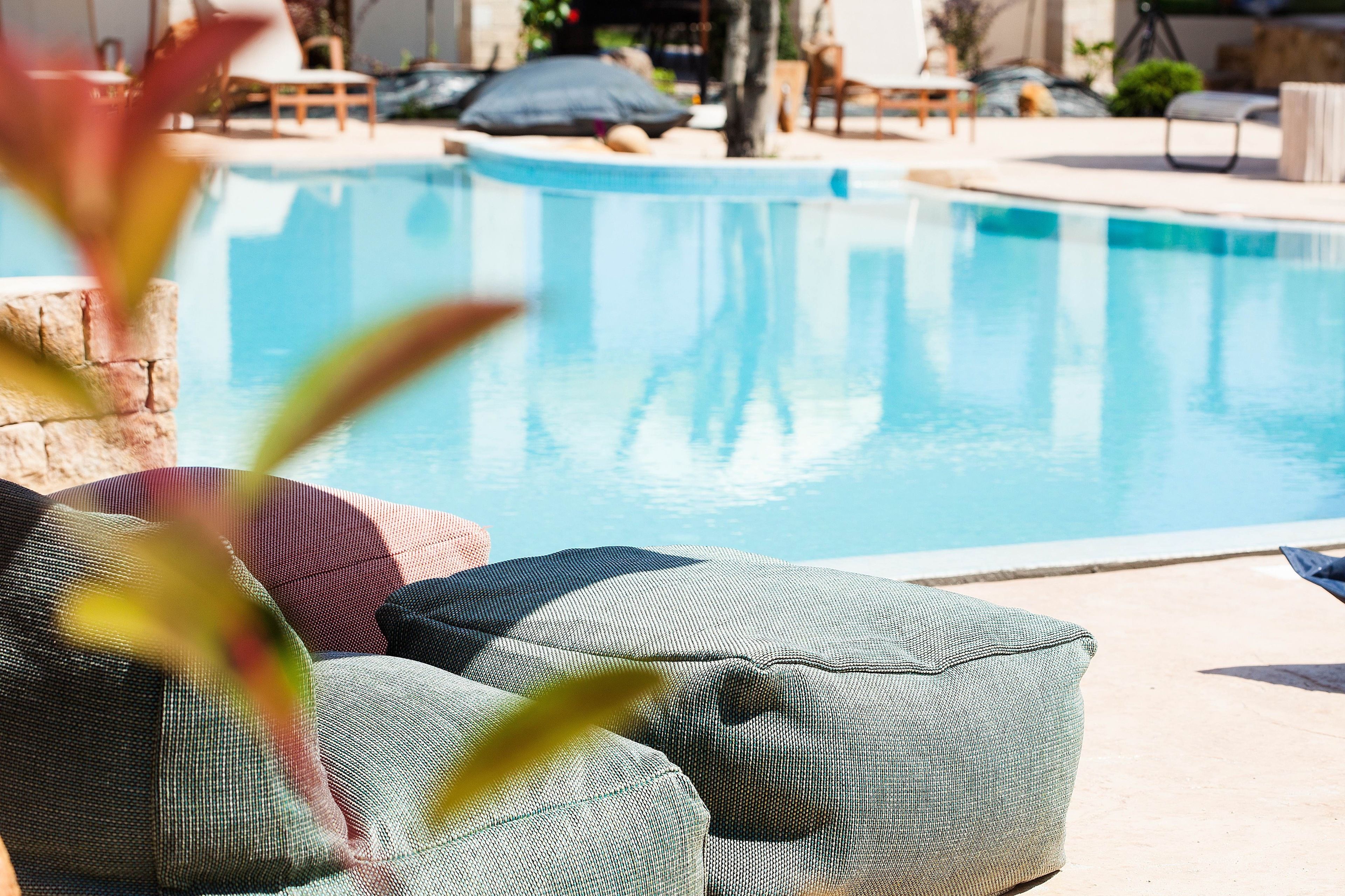 A poolside area with a pool, lounge chairs, and a stone wall.