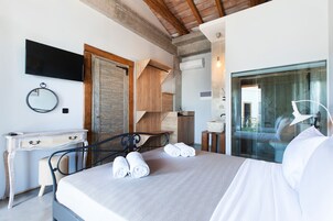 Quarto com uma cama, escrivaninha, cadeira, espelho e televisão.
