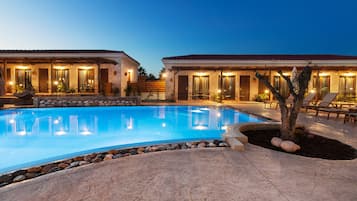 Una piscina al aire libre, sombrillas, sillones reclinables de piscina