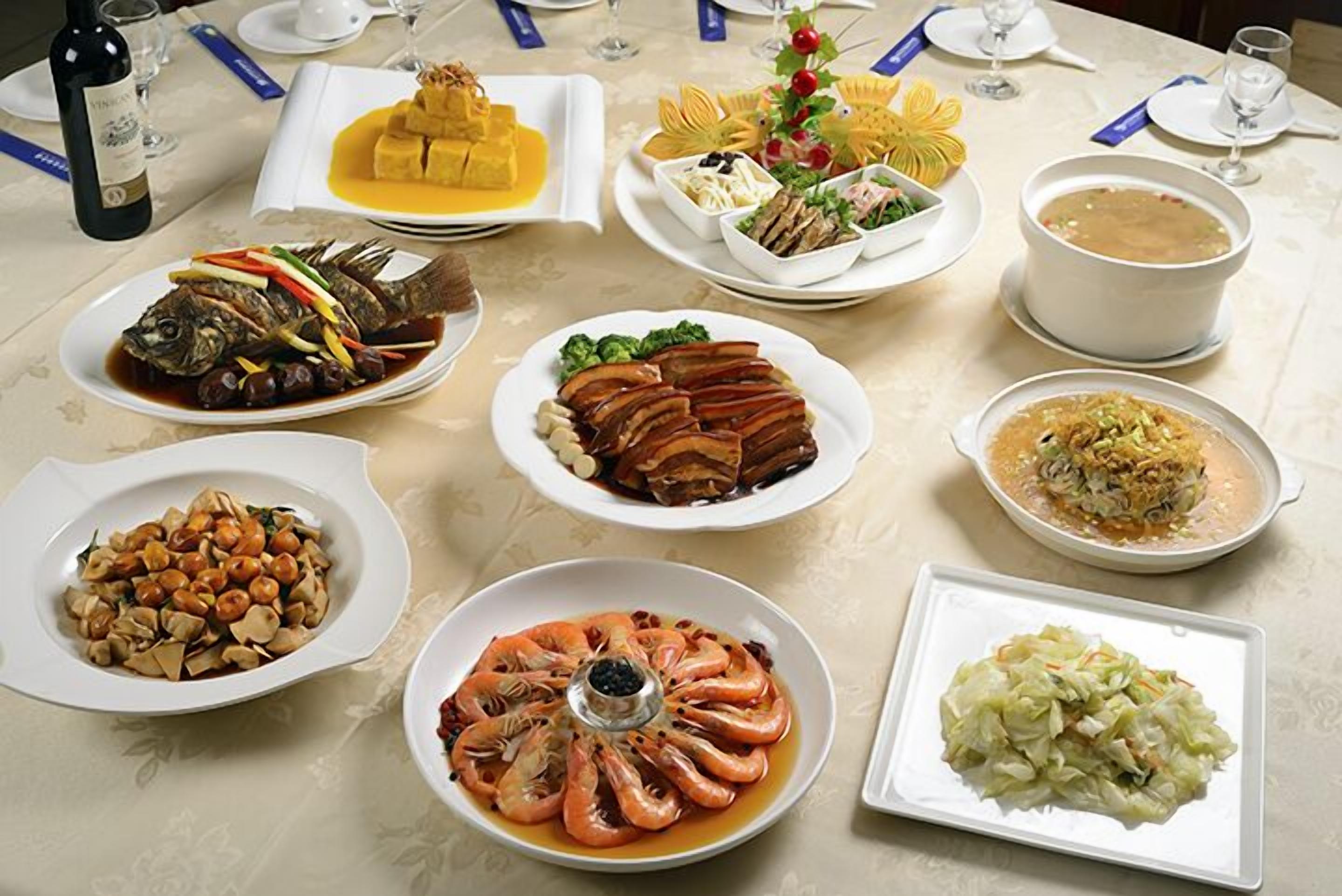 A table set with various dishes, including seafood, vegetables, and a soup.