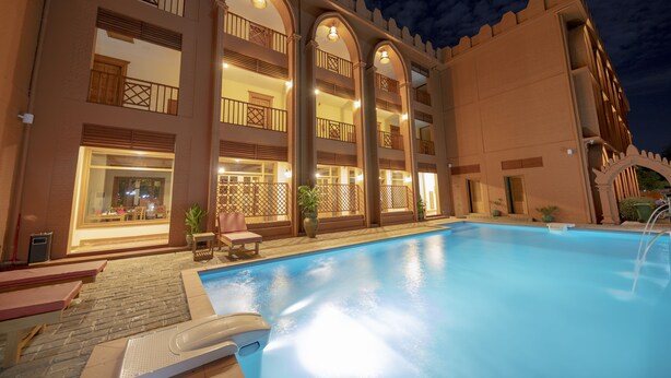 Hotel amb piscina, diversos balcons i una façana ben il·luminada.