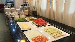 Buffet amb diverses opcions gastronòmiques, com ara tomàquets a làmines, cogombre i síndria.