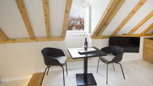 Un coin repas avec une table et deux chaises, une bouteille de vin et des verres posés sur la table.