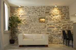 A room with a stone wall, a white sofa, two black chairs, and a potted plant. - Situs Residence (Split)