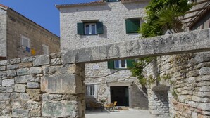 Un bâtiment en pierre doté d’un balcon, d’une porte et d’une petite table entourée de chaises.