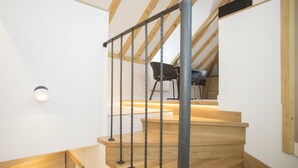 Un escalier en bois avec des rampes en métal et un luminaire fixé au mur.
