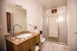 A bathroom with a marble sink, a mirror, a shower with a glass door, and a toilet. - Mare Blu Hotel (Akçaabat)