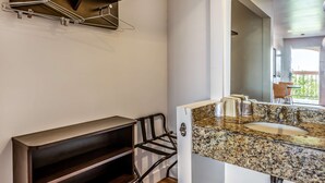 A bathroom with a granite countertop sink, a mirror, and a towel rack. - Motel 6 Gardena, CA - South (Gardena)