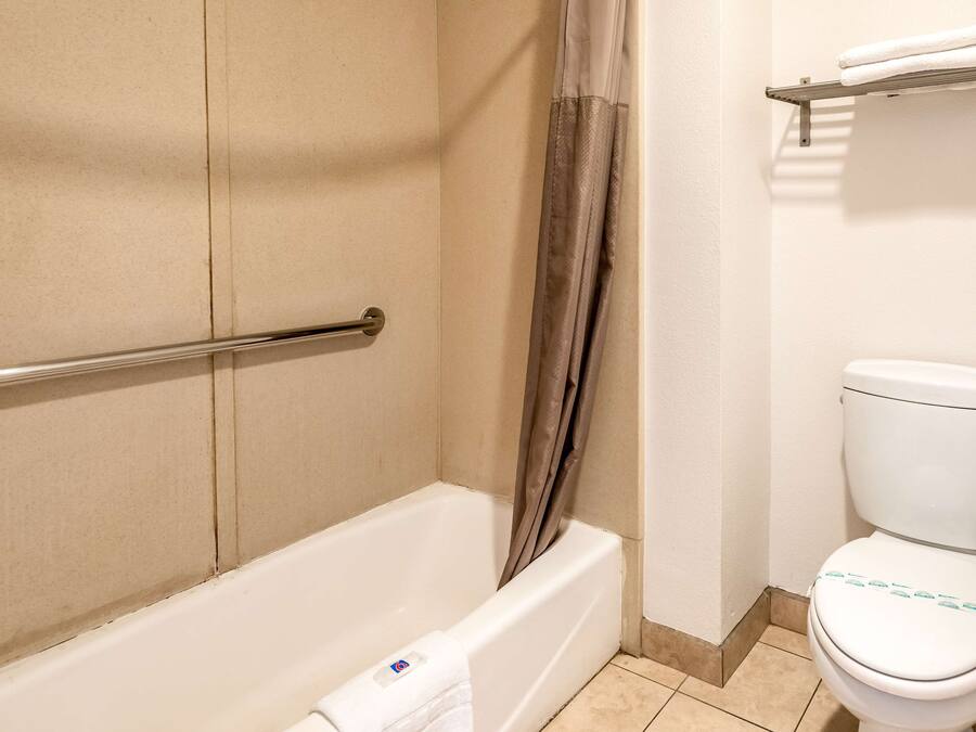 Un baño con una bañera, una cortina de ducha, un inodoro y un perchero para toallas.
