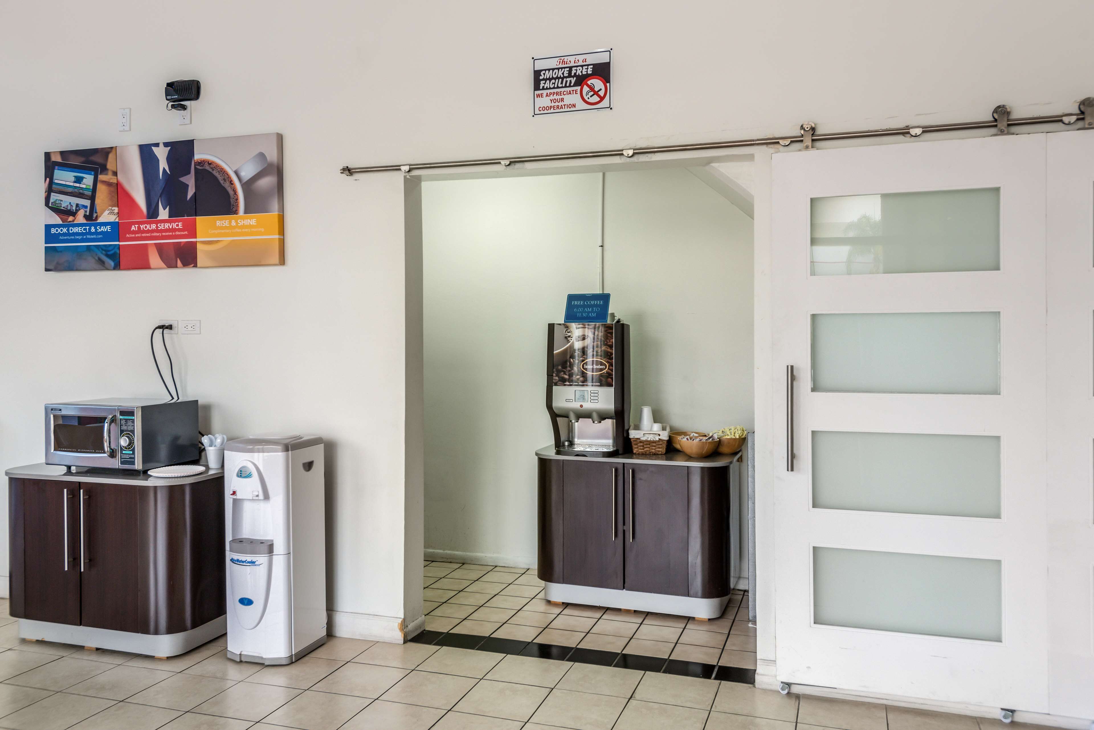 A hotel room with a microwave, coffee machine, and a sign indicating a smoke-free facility.
