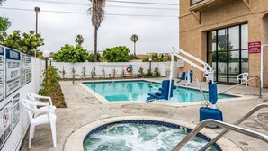 A pool area with a hot tub, lounge chairs, and a lifeguard sign. - Motel 6 Gardena, CA - South (Gardena)