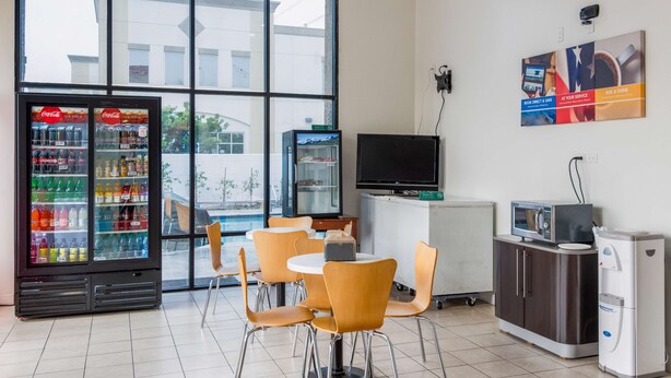 A room with a Coca-Cola refrigerator, a television, and a refrigerator. - Motel 6 Gardena, CA - South (Gardena)