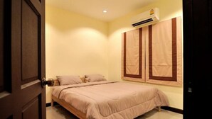 A bedroom with a bed, a wall-mounted air conditioner, and a door. - Cozy House Huahin (Hua Hin)
