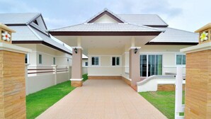 A modern house with a covered patio, a brick pathway, and a small garden area. - Cozy House Huahin (Hua Hin)