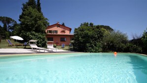 A swimming pool with lounge chairs and umbrellas, surrounded by trees and a large building. - Agriturismo Podere Poggio Ai Cieli (San Gimignano)