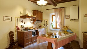 A kitchen with wooden cabinets, a stove, and a table set for dining. - Agriturismo Podere Poggio Ai Cieli (San Gimignano)