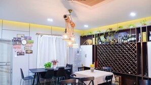 Un comedor con una mesa dispuesta para cuatro personas, una estantería para vinos y una pared decorada con matrículas antiguas y plantas.