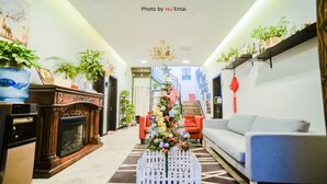 Una sala de estar con chimenea, árbol de Navidad, sofá y una mesa de comedor.